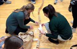 Teilnehmer:innen bauen eind Dominokette aus Holzklötzen