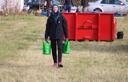 Praktikantin schleppt Gießkannen zu den Pflanzlöchern.