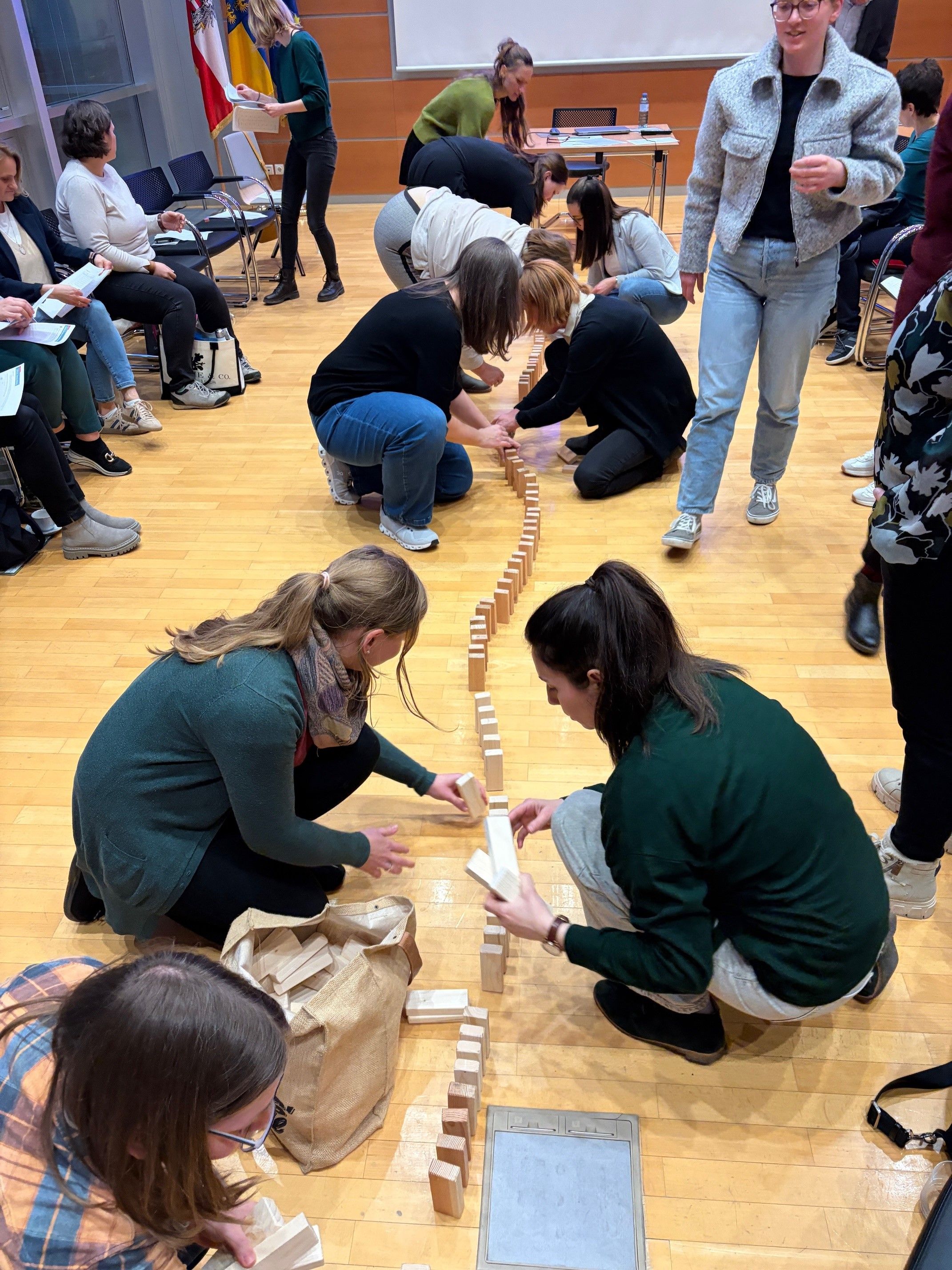 Teilnehmer:innen bauen eind Dominokette aus Holzklötzen