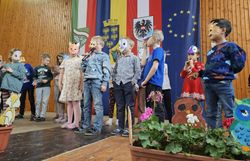 Kinder mit Tiermasken tragen auf der Bühne das Gedicht "Tiere im Wald" vor.