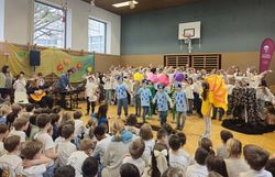 Kinder performen das Musical „Friends of the Earth“ - KInder in tollen Verkleidungen mit Chor im Hintergrund