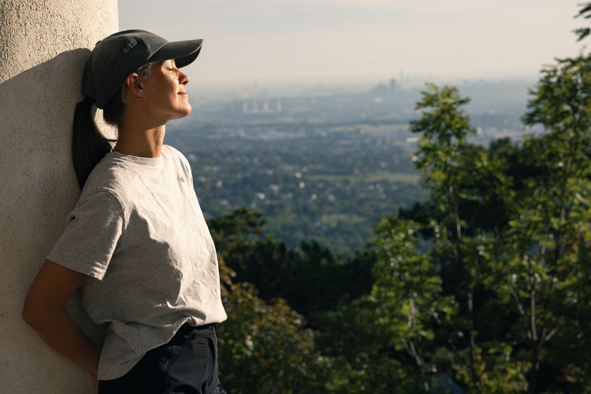 Frau lehnt gegen Säule im Husarentempel, genießt die Sonne im Gesicht