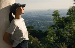 Frau lehnt gegen Säule im Husarentempel, genießt die Sonne im Gesicht