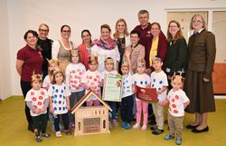 Ehrengäste, Kindergartenleitung und Kinder posieren mit der Naturpark-Kindergarten Urkunde für ein Gruppenfoto.