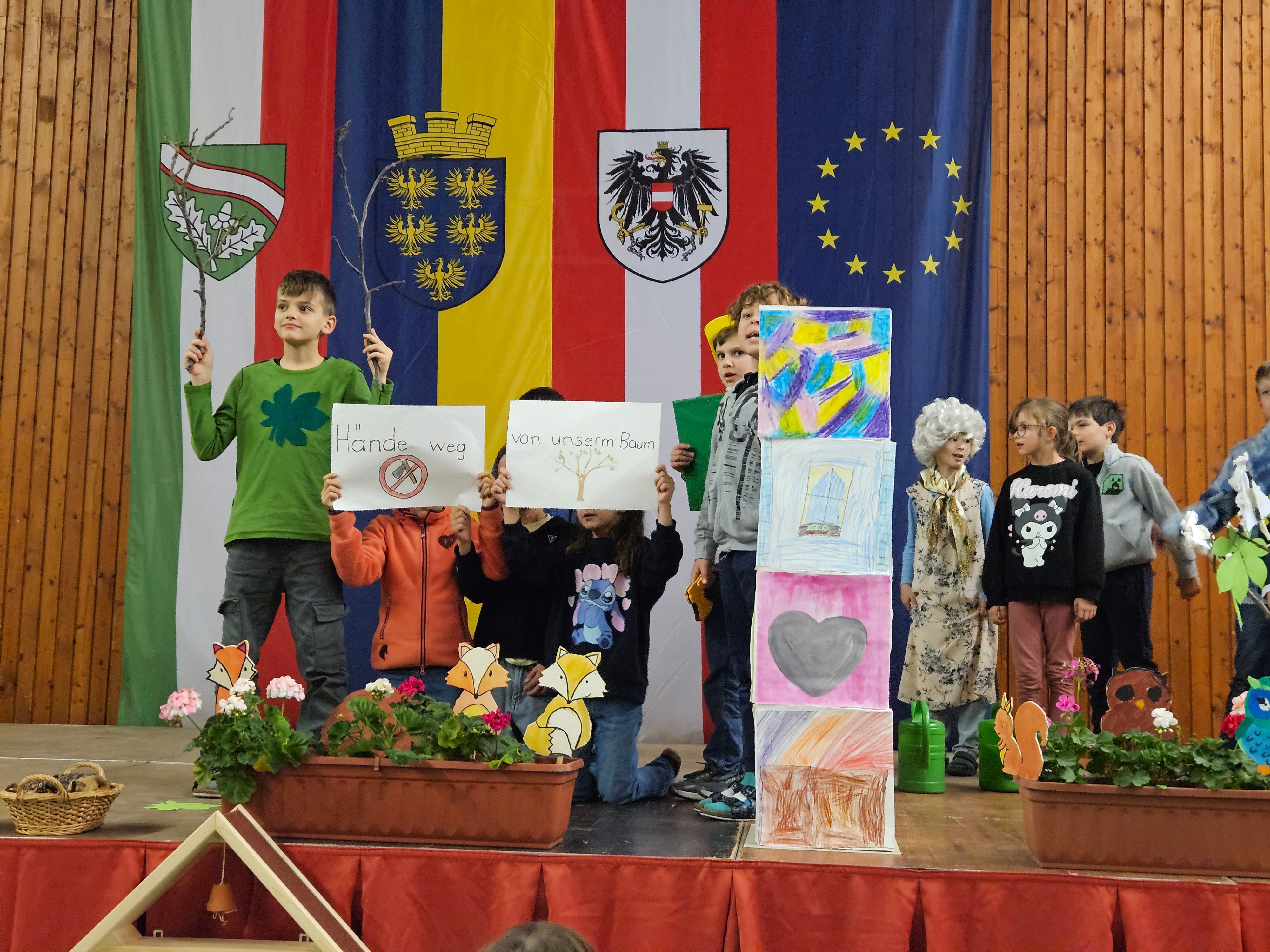 Kinder halten selbstgestaltene Plakate und tragen das Lied "Halt, das ist unser Wald!” vor.