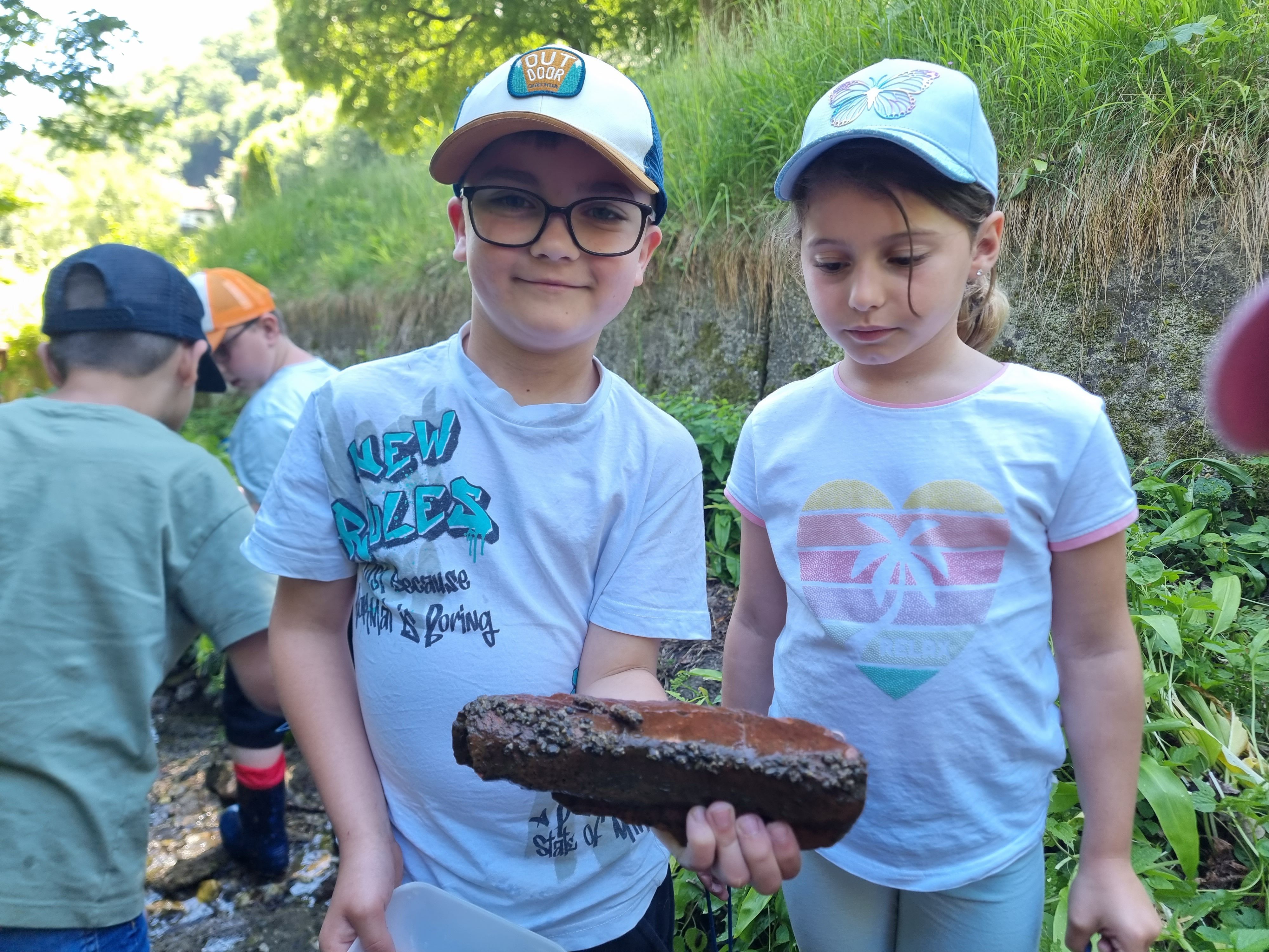 Kinder mit stein voller Köcherfliegenlarven (Trichoptera) 