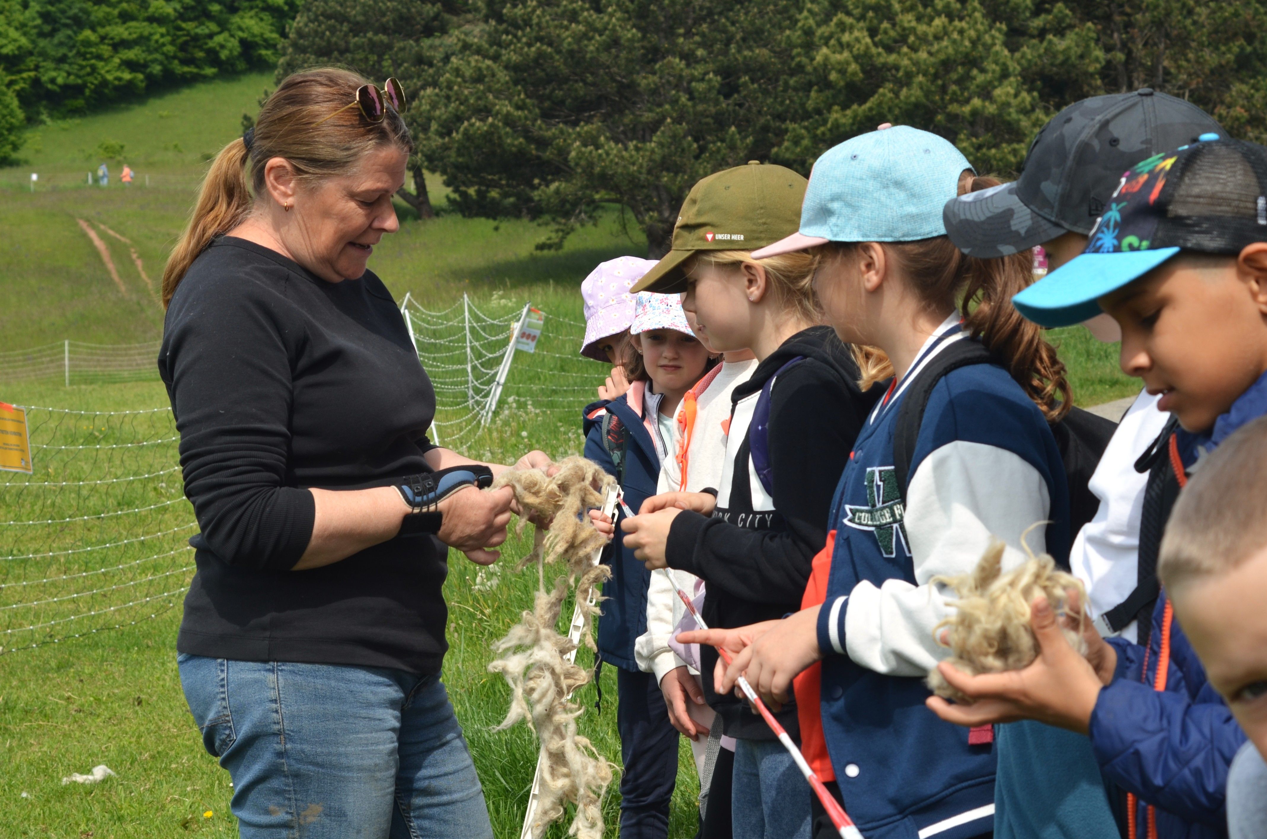 Schäferin und Kinder erfühlen die Schafswolle mit allen Sinnen.