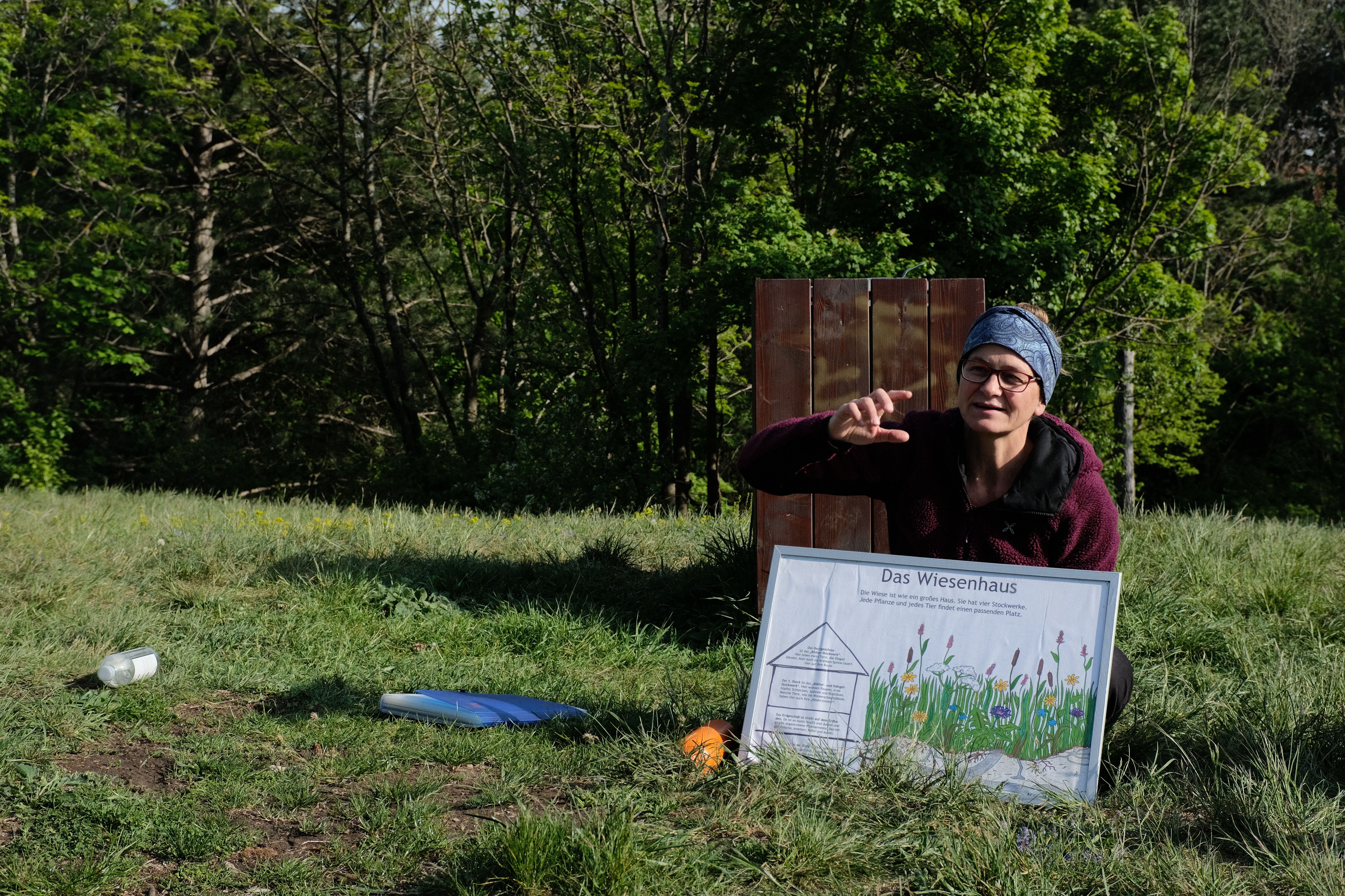 Naturvermittler:in Alex erklärt die Stockwerke des Wiesenhauses und die Umsetzung mit den Kindern.