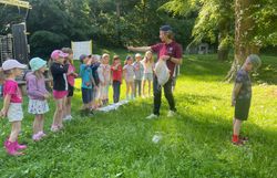 Naturvermittler zeigt den Kindern einen Gegenstand