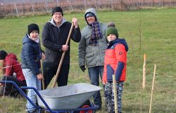 Familie füllt die Pflanzlöcher mit Erde auf.
