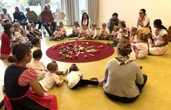 Kinder, Pädagoginnen und Ehrengäste sitzen im Kreis feiern Erntedank.