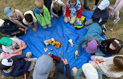 Kinder im Sitzkreis um Wiesen-Gegenstände