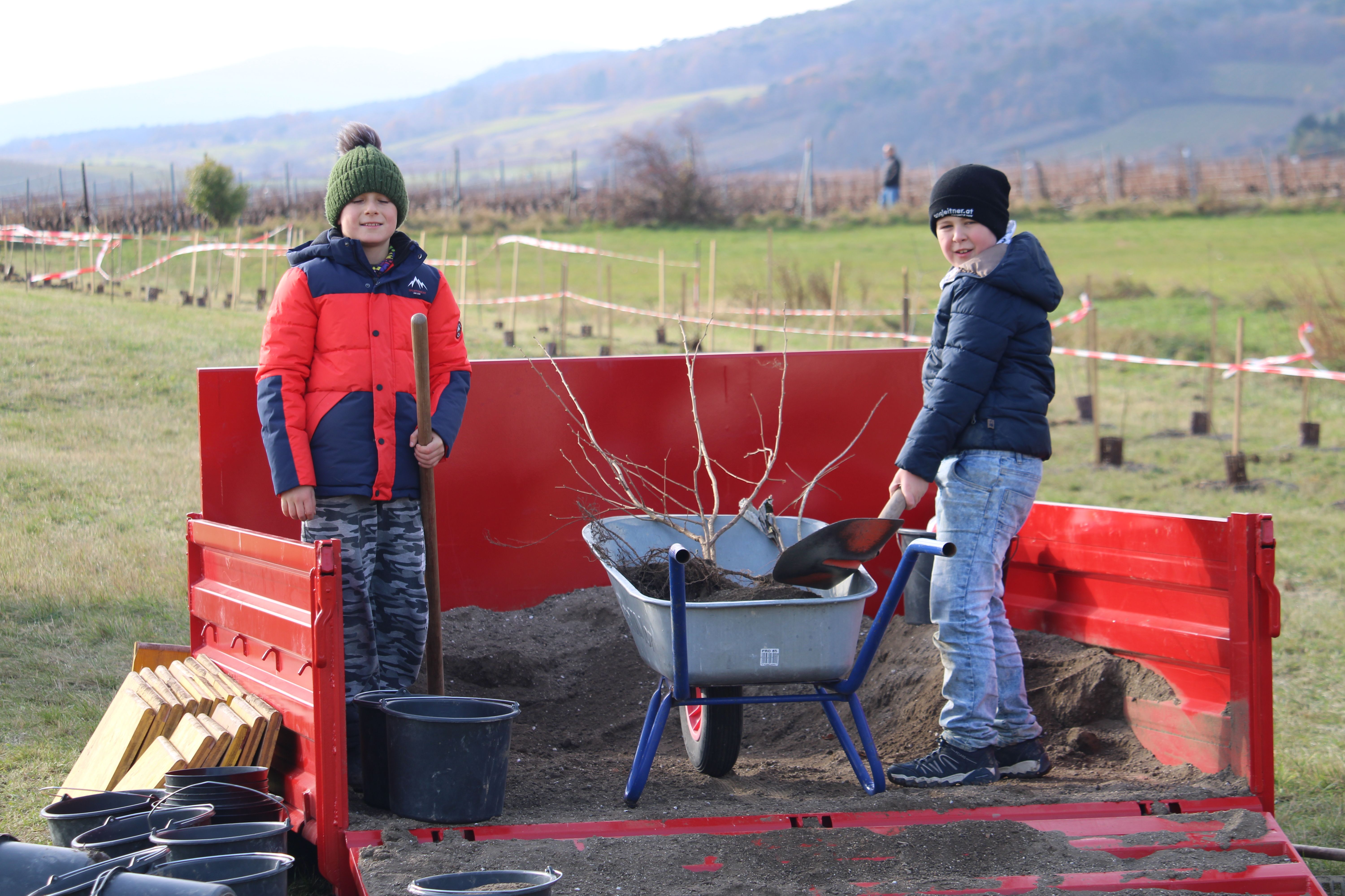 Kinder befüllen Schubkarre mit Erde.