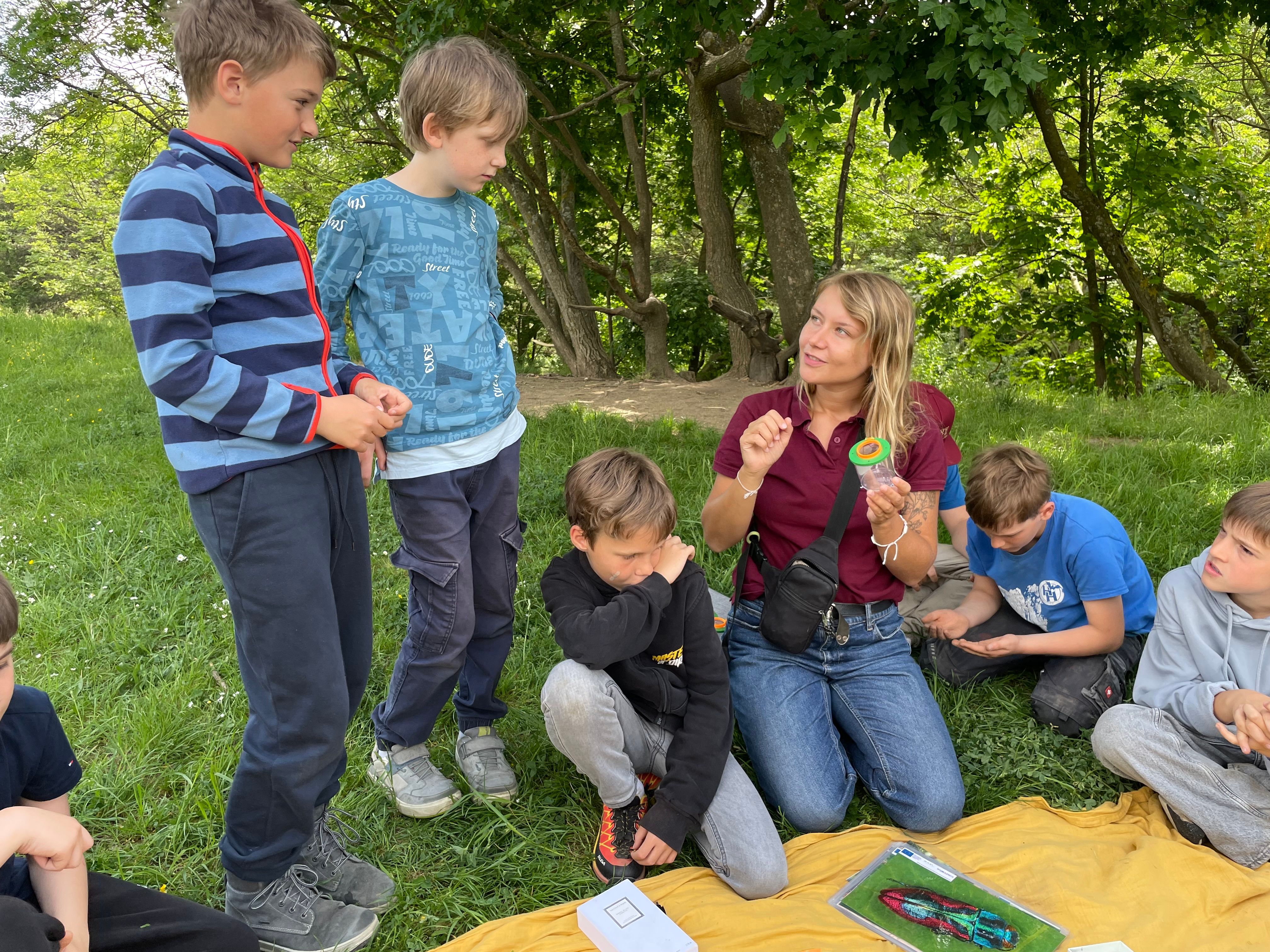 Naturvermittlerin mit Kindern beim Insektenbestimmen