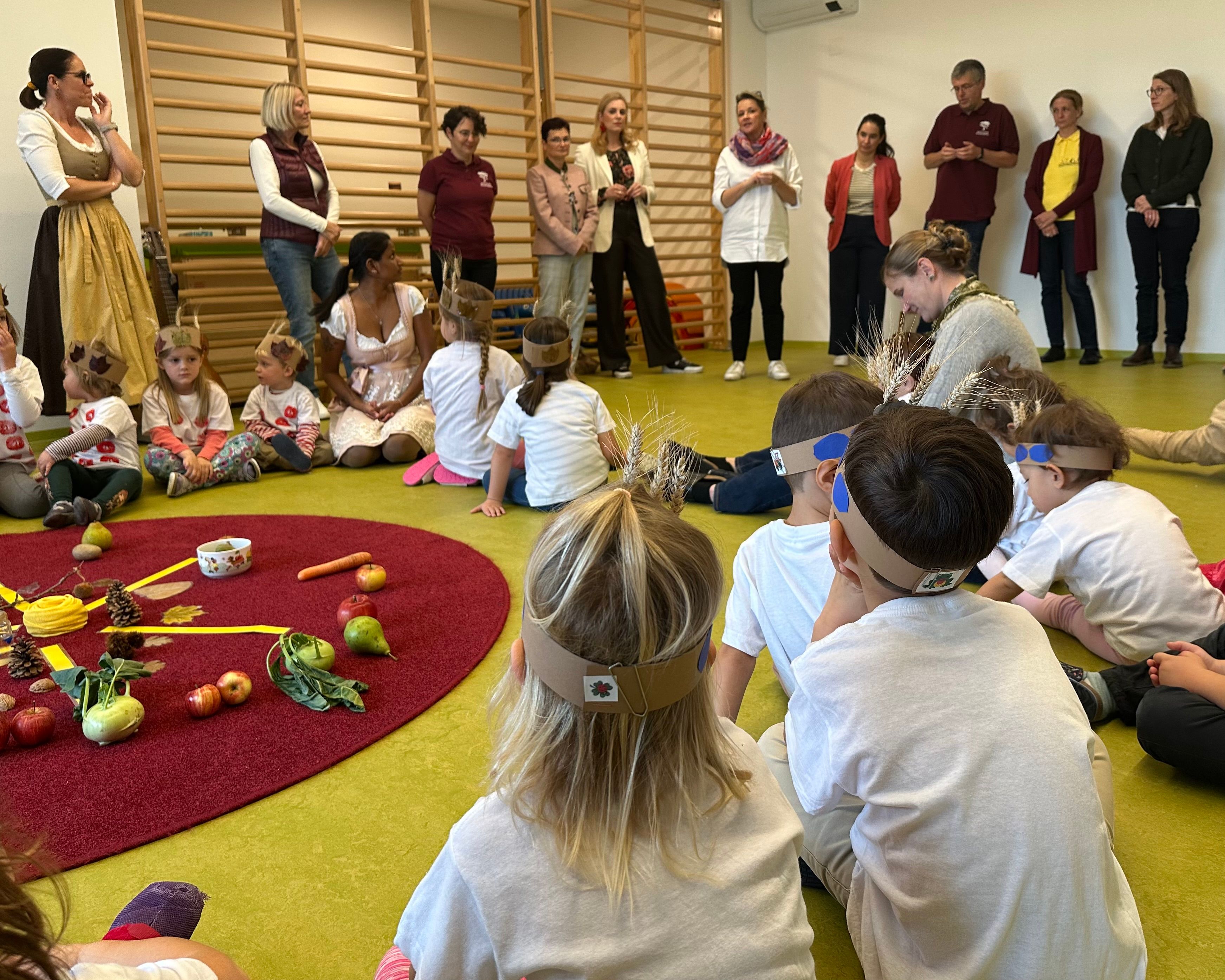 Kindergartenkinder sitzen im Kreis und hören der Rede von Frau Landesrat Rosenkranz zu.