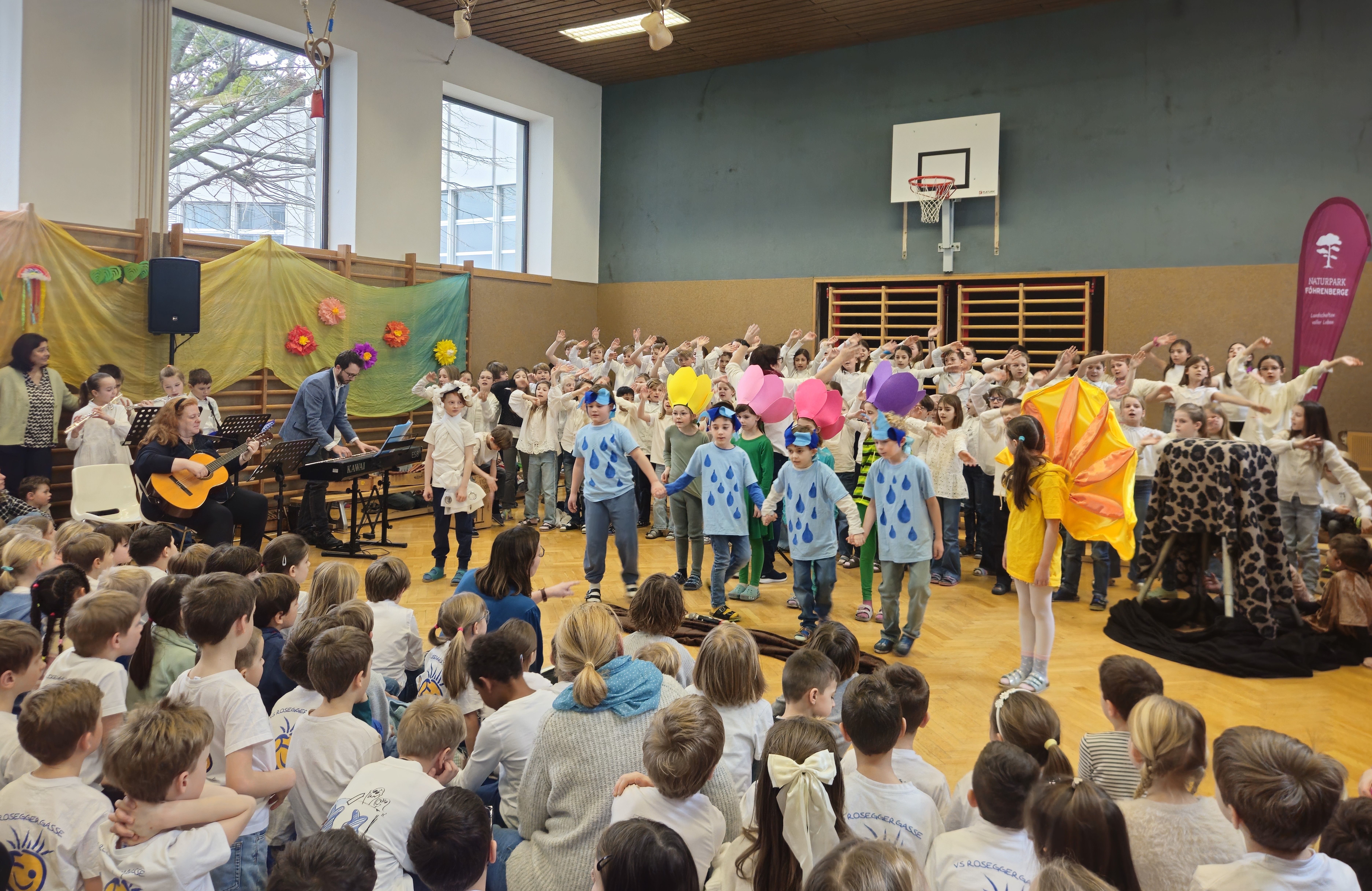 Kinder performen das Musical „Friends of the Earth“ - KInder in tollen Verkleidungen mit Chor im Hintergrund