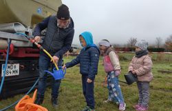 Naturvermittler hilft den Kindern die Gießkannen anzufüllen.