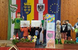 Kinder halten selbstgestaltene Plakate und tragen das Lied "Halt, das ist unser Wald!” vor.