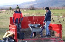 Kinder befüllen Schubkarre mit Erde.