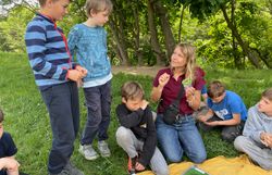 Naturvermittlerin mit Kindern beim Insektenbestimmen