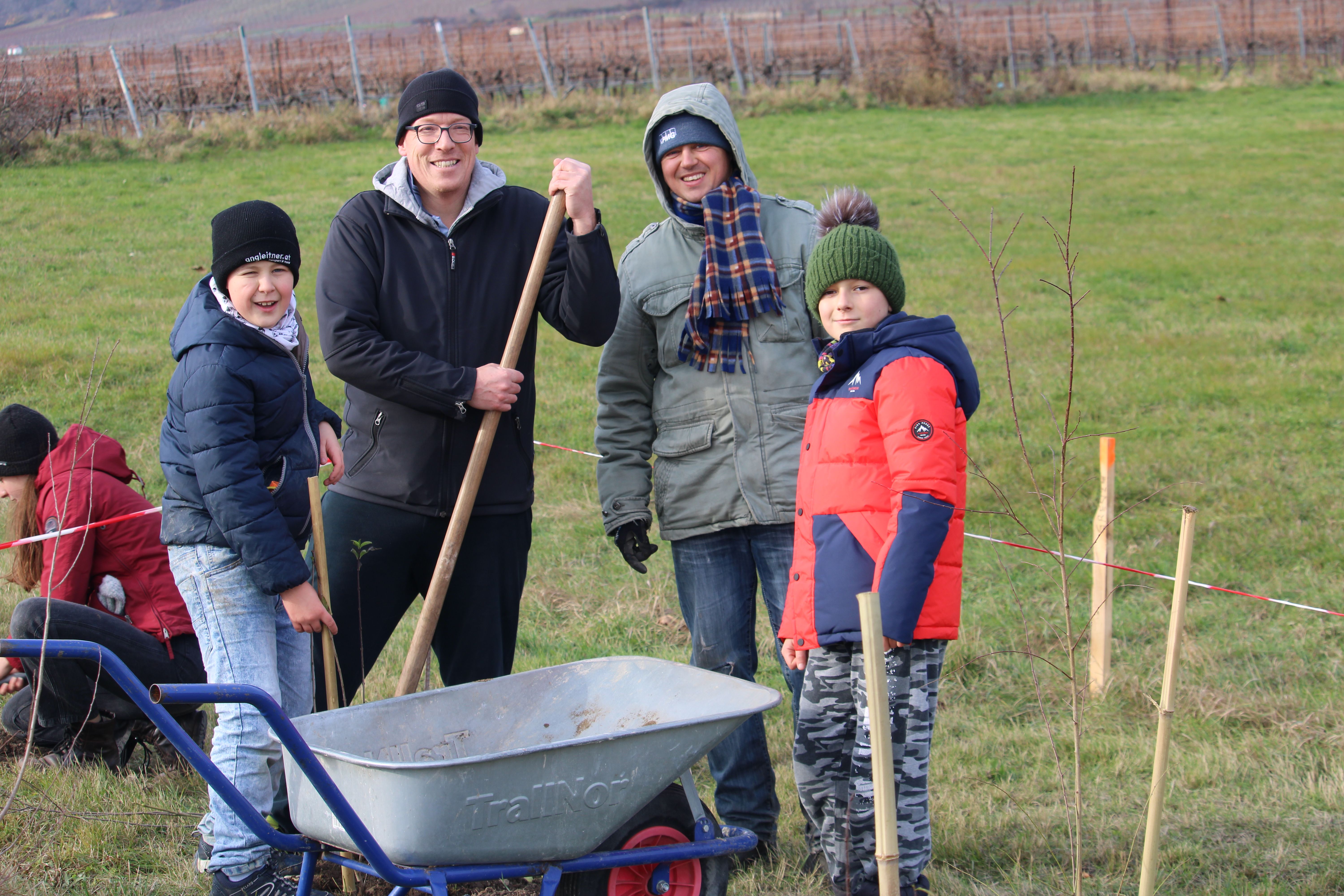 Familie füllt die Pflanzlöcher mit Erde auf.