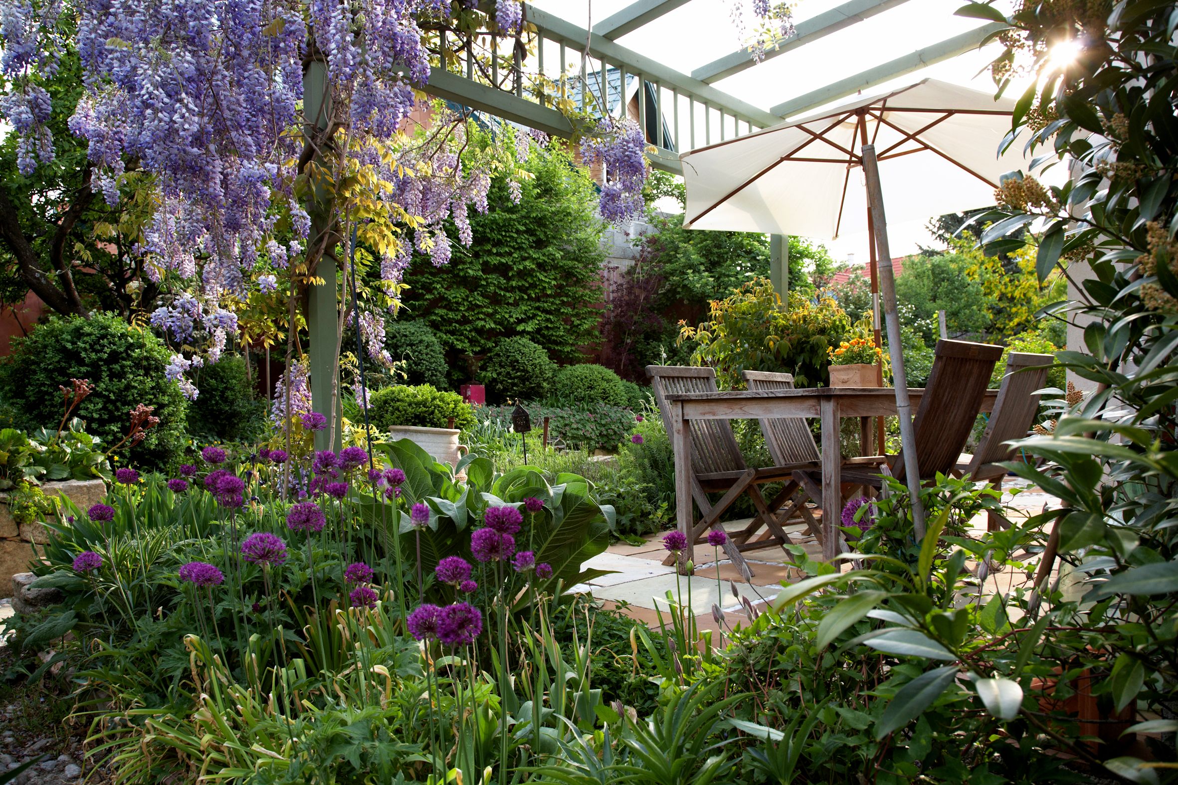 Blick in einen schön gestalteten Garten mit Terrasse uns Sitzgelegenheiten