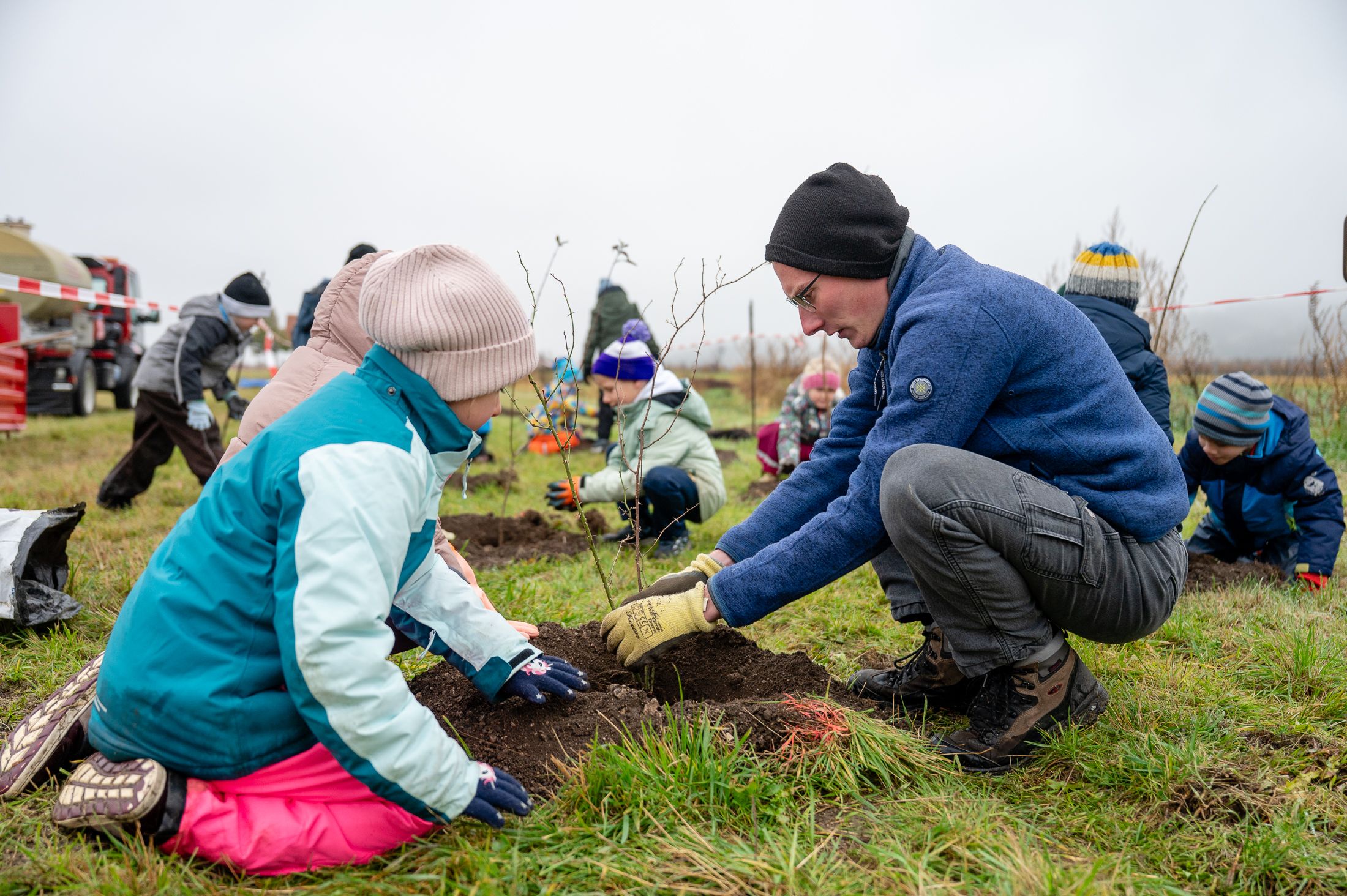 Naturvermittler unterstützt die Schüler:innen bei der Pflanzung der Gehölze.