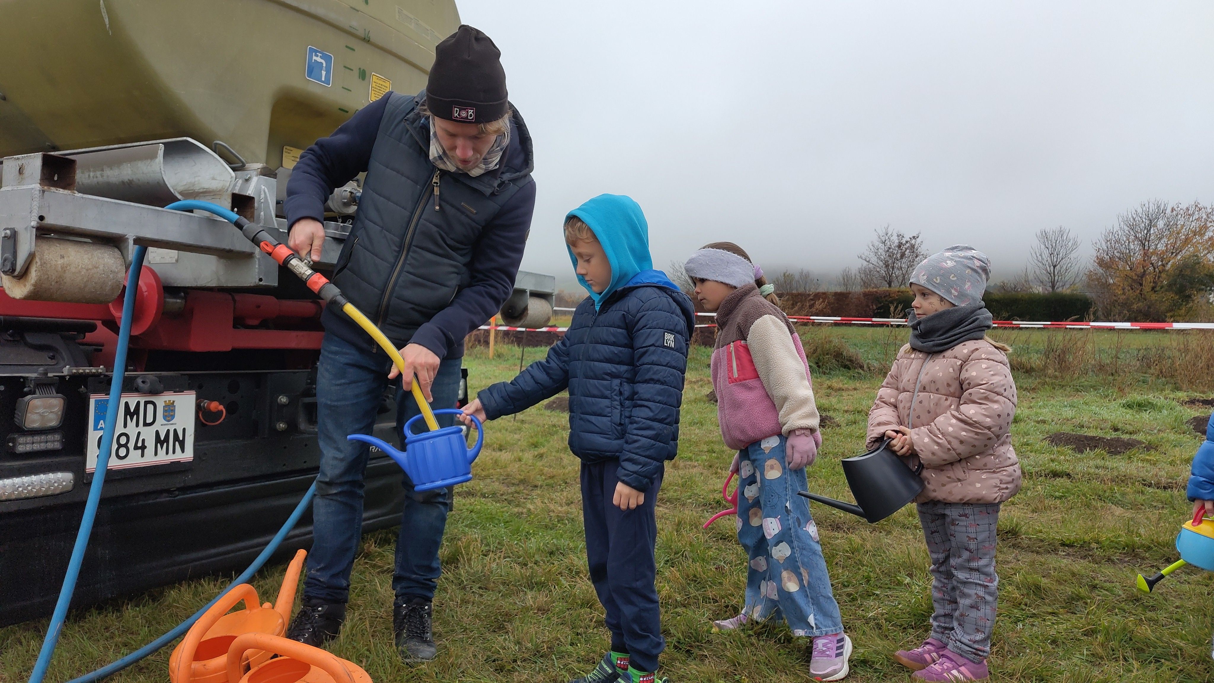 Naturvermittler hilft den Kindern die Gießkannen anzufüllen.